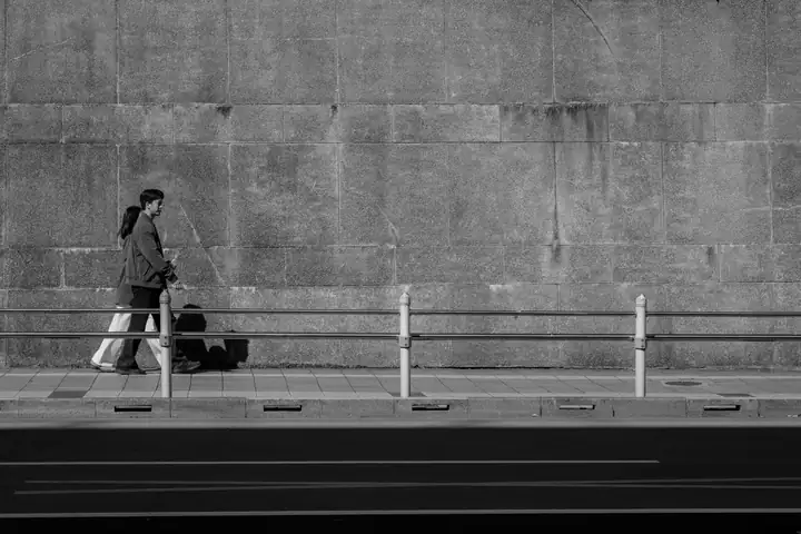 Una pareja camina junto a un muro